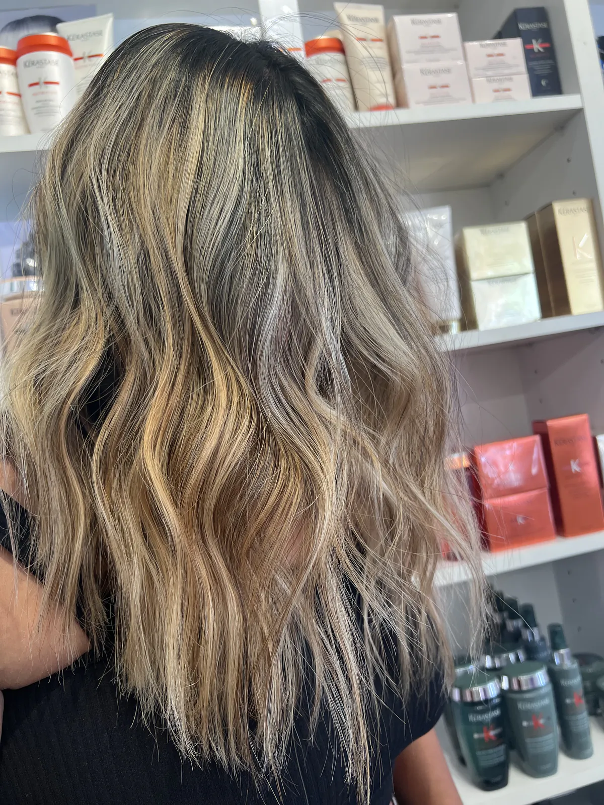 Smoky-root balayage by Emily melting into bright golden-blonde ribbons, styled in loose waves
